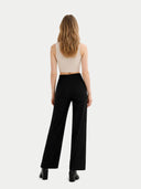 Woman wearing a beige top, light pink cardigan, black pants, and black boots on a white background #color_off-white