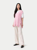 Woman wearing a pink top and white pants on a white background