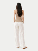 Woman wearing a beige sleeveless cashmere top against a white background. #color_warm-grey