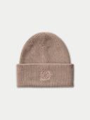 A ribbed knit beanie hat in a dusty rose pink color, featuring a small tonal embroidered logo on the front of the folded cuff, set against a light gray background.