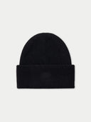 A black ribbed knit beanie hat with a folded cuff, featuring a subtle tonal embroidered logo on the front, set against a light gray background.