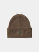 A brown ribbed knit beanie hat with a folded cuff and a small green embroidered four-leaf clover logo on the front, shown against a light gray background.