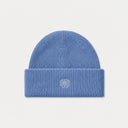A ribbed knit beanie hat in a light beige or cream color, featuring a small tonal embroidered geometric logo on the front of the folded cuff, set against a solid off-white background.