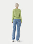 Person wearing a green sweater and blue jeans on a white background. #color_jade-green