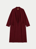 A long burgundy open-front coat with wide lapels and two front patch pockets, shown flat against a light gray background. A small tan brand label is visible at the inner collar.