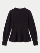 A black long-sleeve knit top with a crew neck and a flared peplum-like hem, shown flat against a light gray background.