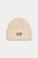 A cream-colored ribbed knit beanie hat with 'GOBI EST.1981' printed in black on the front cuff, set against a solid light gray background.
