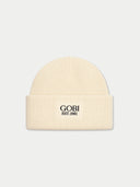 A cream-colored ribbed knit beanie hat with 'GOBI EST.1981' printed in black on the front cuff, set against a solid light gray background.