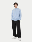 Person wearing a light blue cashmere sweater, black pants, and white shoes on a white background #color_muted-blue