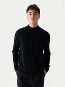 Model wearing black zip-up knit with stand collar, front view, hands in pockets
