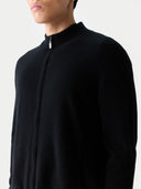 Person wearing a black long-sleeve shirt with a high collar on a black background