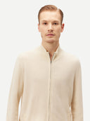 Cream-colored zip-up cashmere sweater on a light gray background #color_off-white