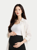 close up of a woman wearing a white shirt and black maternity pants on a white background