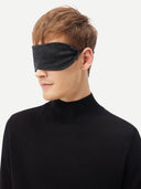 A man wearing the charcoal cashmere eye mask, head turned to the side.