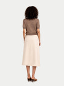 Woman wearing a brown top and beige skirt on a white background