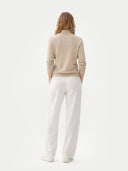 A light beige knit zip-up cashmere jacket with a mock neck, ribbed cuffs, and side pockets, displayed against a light gray background. #color_dusty-beige