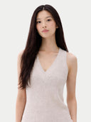 Woman wearing a light pink sleeveless cashmere top and white pants on a white background. #color_pure-white