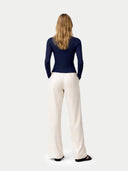 Person wearing a navy long-sleeve top and white pants on a white background #color_dark-indigo