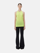 A woman wearing a sleeveless cashmere top in green, paired with black pants.#color_lime-yellow