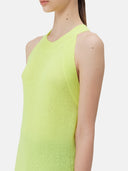 A woman wearing a sleeveless cashmere top in green, paired with black pants.#color_lime-yellow