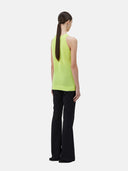 A woman wearing a sleeveless cashmere top in green, paired with black pants.#color_lime-yellow