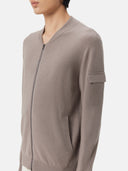 A gray knit zip-up cashmere bomber with a V-neck, ribbed cuffs and hem, and a sleeve pocket, shown against a light gray background. #color_cool-gray