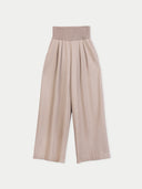 A pair of high-waisted, wide-leg cropped pants in a light beige or dusty rose color, featuring a textured waistband and pleated front, shown against a plain light gray background.