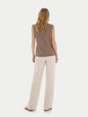 Woman wearing a brown sleeveless top and beige pants on a white background. #color_taupe