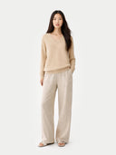 Woman wearing a beige cashmere sweater and pants on a white background #color_beige