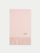 A pale pink cashmere scarf with fringes displayed against a plain background.