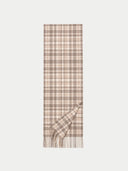 A long plaid scarf in beige and taupe-brown tones, shown flat against a light gray background with one corner folded over to reveal the fringed edge.