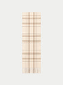 A long rectangular scarf with a beige and cream plaid pattern and fringed ends, shown flat against a light gray background.
