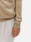A light beige knit zip-up cashmere jacket with a mock neck, ribbed cuffs, and side pockets, displayed against a light gray background. #color_dusty-beige