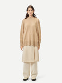 A woman wearing a beige loose-fit cashmere sweater. #color_beige
