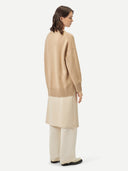 A woman wearing a beige loose-fit cashmere sweater. #color_beige
