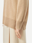 A woman wearing a beige loose-fit cashmere sweater. #color_beige