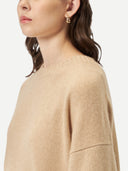 A woman wearing a beige loose-fit cashmere sweater. #color_beige