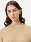 A woman wearing a beige loose-fit cashmere sweater. #color_beige
