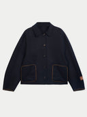 A dark navy blue cropped jacket with a pointed collar, button front, and two large front patch pockets with contrasting brown piping, shown on a light gray background.