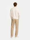 Man wearing a white sweater and beige pants on a white background #color_cream-white