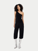 Woman wearing a black one-shoulder top with silver boots on a white background #color_black
