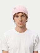 front view of a man wearing a pink beanie with a logo on a white background.
