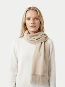 Woman wearing a beige scarf on a white background.