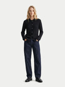 Person wearing a black shirt and dark jeans on a white background.