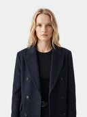 close up front view of a woman wearing a black coat on a light gray background.