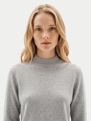 The Cashmere Mock Neck Sweater in light gray, shown worn.