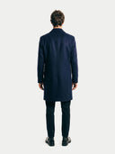 Man wearing a navy overcoat on a white background