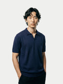 Man wearing a navy blue cashmere polo shirt against a plain background. #color_iris-navy
