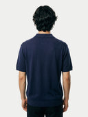 Man wearing a navy blue cashmere polo shirt against a plain background. #color_iris-navy