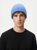 Man wearing a blue knit beanie against a white background.